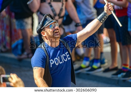 STOCKHOLM, SWEDEN - AUGUST 1, 2015: Happy man in leather and a police t-shirt at the Pride parade in Stockholm. Approx 400.000 spectators at the streets.