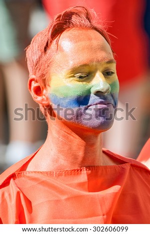 STOCKHOLM, SWEDEN - AUGUST 1, 2015: Colorful man with red hair and face painted in rainbow colors at the Pride parade in Stockholm. Approx 400.000 spectators at the streets.