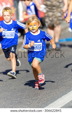 STOCKHOLM, SWEDEN - AUGUST 15, 2015: Girl in face painting in front at the Minimil for the youngest runners at Midnattsloppet. The track is 300 meters and the runners are aged 2-8 years.