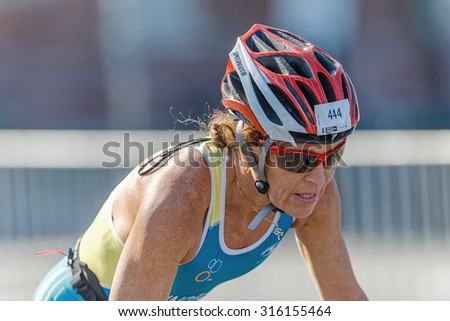 STOCKHOLM - AUG 23, 2015: Closeup of a older woman triathlete on a bike in the old town in the ITU World Triathlon event in Stockholm.