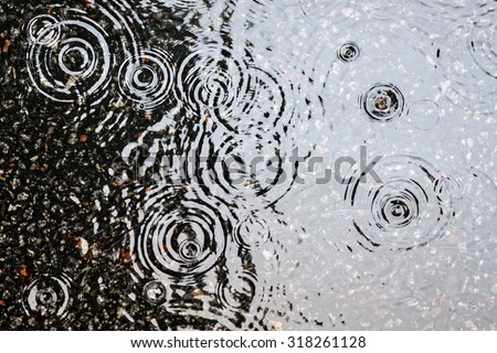 Rain on asphalt or tarmac road creating ripples, high contrast during autumn.