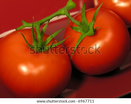 The perfect red tomatoes on a red dish, close-up