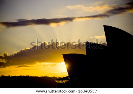 Warm sunrise bursting behind the silhouette of the Sydney Opera House behind the silhouette of the Sydney Opera House
