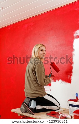 Girl painting living room in a red color.