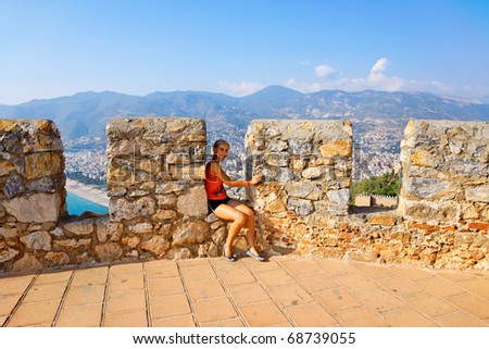 Young girl sitting on ancient castle defense wall.