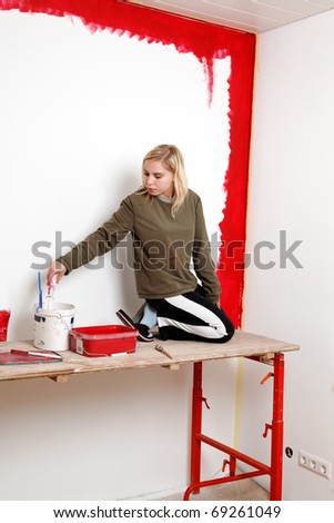 Girl painting living room in a red color.
