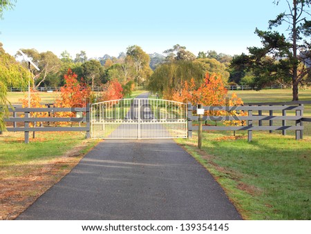 Ornate wrought iron gates on a country property driveway in a colourful autumn country setting
