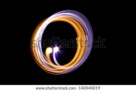 Long exposure motion circles of light abstract background with the colours of purple and gold on a black background