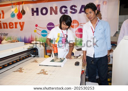 BANGKOK - JUNE 28 :Unidentified workers show digital t-shirt printer work with Sewing  machine at Garment Manufacturers Sourcing 2014 2014 on June 28,2014 in BITEC ,Bangkok,  Thailand.