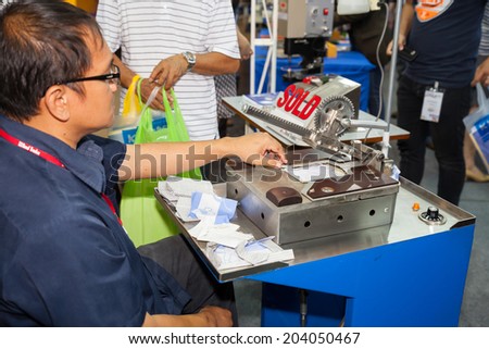 BANGKOK - JUNE 28 :Unidentified worker show cutting shirt pocket  machine at Garment Manufacturers Sourcing 2014 on June 28,2014 in BITEC  ,Bangkok, Thailand.