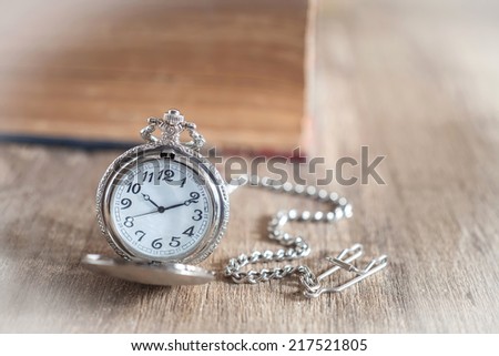 Pocket watch and old book on wood background,still life