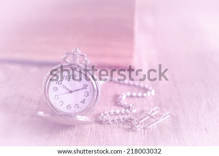 Pocket watch and old book on wood background,still life