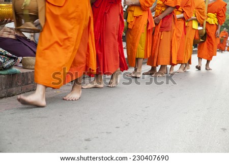 LUANG PRABANG, LAO - OCTOBER 22: Every day very early in the  morning, the monks walk the streets to beg give food  offerings to a Buddhist monk on OCTOBER 22, 2014 in Luang  Prabang, Laos