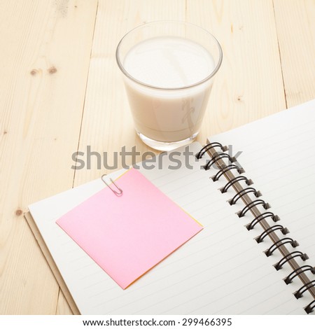 Note book with cup of milk on a wooden desk