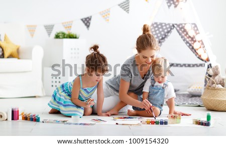 children's creativity. mother and children draw paints in the playroom