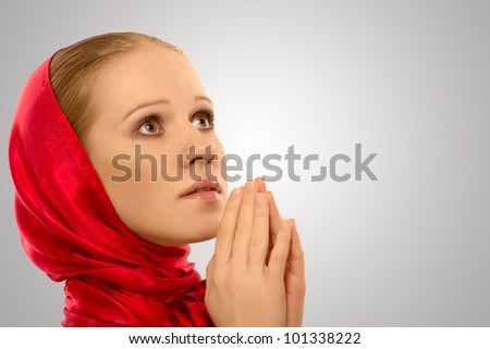 young religious woman in a red shawl prays to God