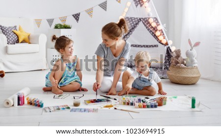 children's creativity. mother and children draw paints in the playroom
