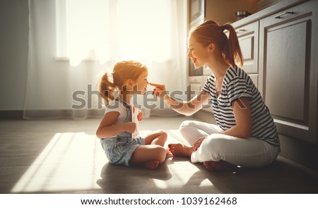 happy mother\'s day! child daughter congratulates her mother and on  floor in kitchen read postcard