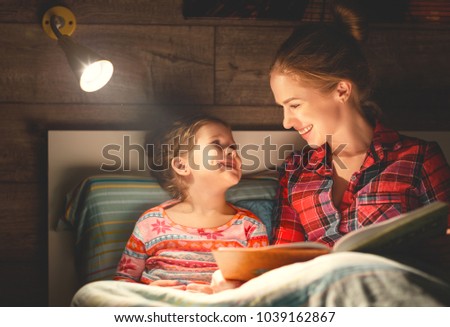 mother and child daughter reading book in bed before going to sleep