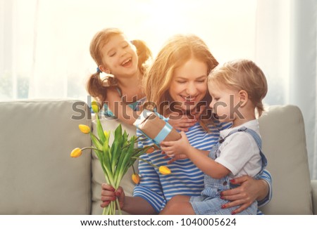 Happy mother\'s day! Children congratulates moms and gives her a gift and flowers tulips