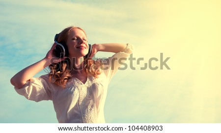 beautiful girl listening to music on headphones in the sky