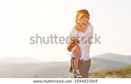 father\'s day. child daughter sits on her dad shoulders outdoors on a summer beach