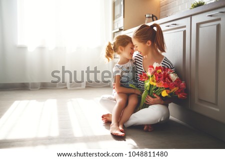 happy mother\'s day! child daughter congratulates mother and gives a bouquet of flowers to tulips