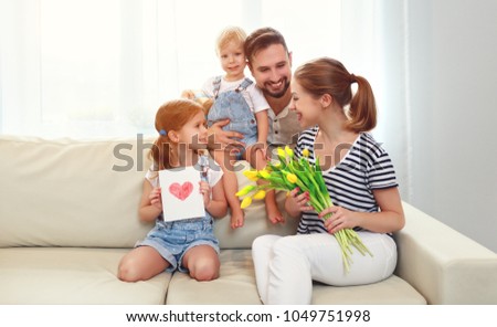 happy mother's day! father and children congratulate mother on holiday and give flowers