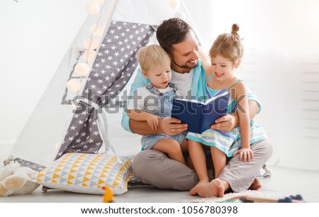 family father reading to children book in tent in playroom at home