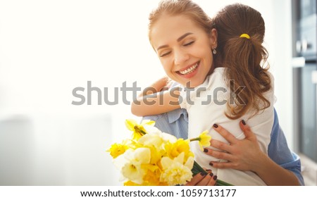 happy mother\'s day! child daughter congratulates mother and gives a bouquet of flowers to narcissus and gift