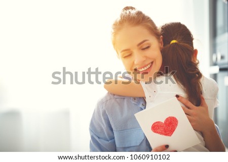 Happy mother\'s day! Child daughter congratulates moms and gives her a postcard
