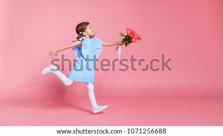 funny child girl runs and jumps with bouquet of flowers on a colored background