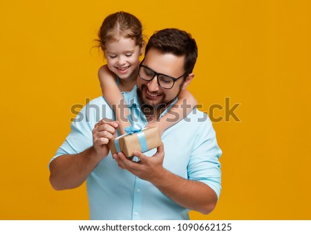 happy father\'s day! cute dad and daughter hugging on colored yellow background