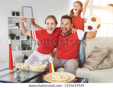A family of fans watching a football match on TV at home