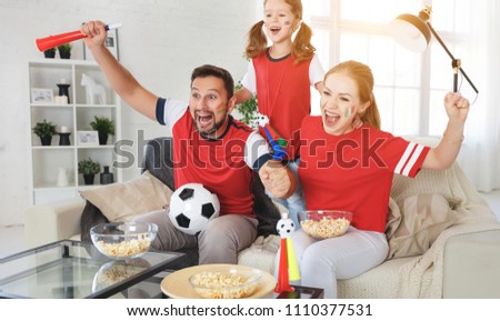 A family of fans watching a football match on TV at home