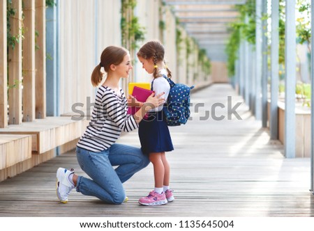 first day at school. mother leads a little child school girl in first grade