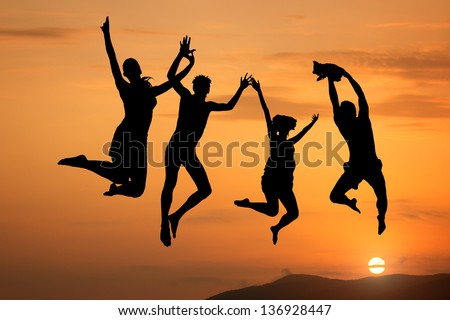 Silhouette of happy people jumping at sunset and sea