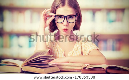 funny crazy girl student with glasses reading books in the library