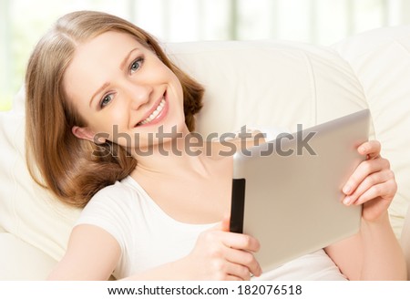 happy woman with tablet pc  on the sofa at home