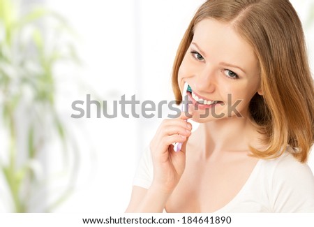 Healthy happy young woman with snow-white smile brushing her teeth with a toothbrush