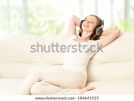 beautiful girl in headphones enjoying music at home on the couch