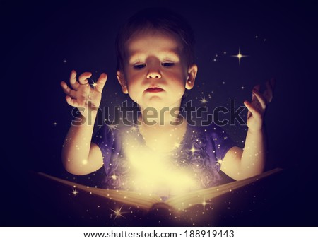 baby girl with magic book on a dark background