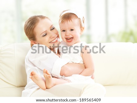 happy family. Mother and baby daughter plays, hugging, kissing at home on the sofa