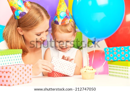 happy birthday. mother giving a gift to his little daughter with balloons and cake