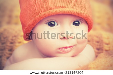 cute happy newborn baby in knitted orange hat cap