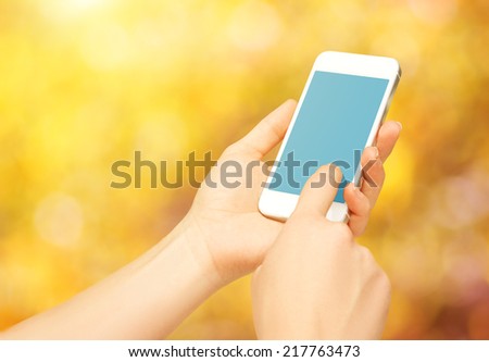 blank empty phone device in the hands of a woman on the nature in autumn
