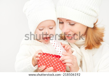 happy family mother and daughter in white hats with Christmas present in winter