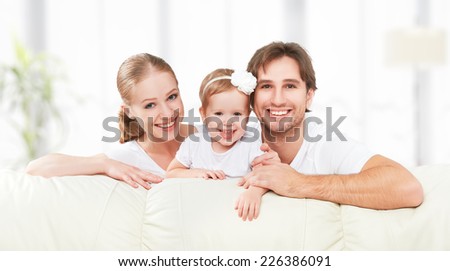 Happy family mother, father, child baby daughter at home on the sofa playing and laughing