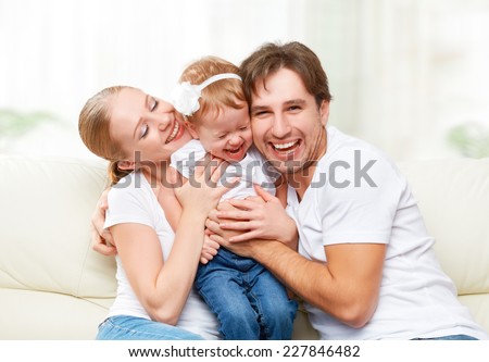 happy family mother, father, child baby daughter at home on the sofa playing and laughing