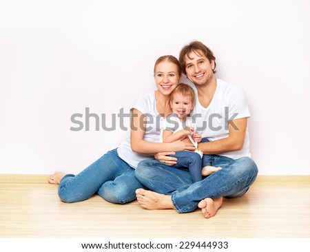 Happy family on the floor near the empty blank  wall in the apartment bought on mortgage